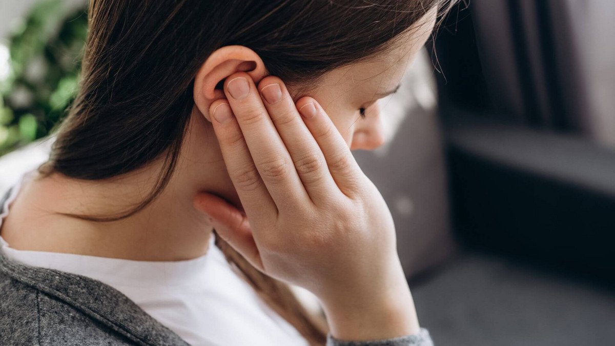 Woman holding a hand over her ear